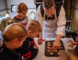 An interpreter in historic costume helps children bake cookies in the Rutherford House kitchen